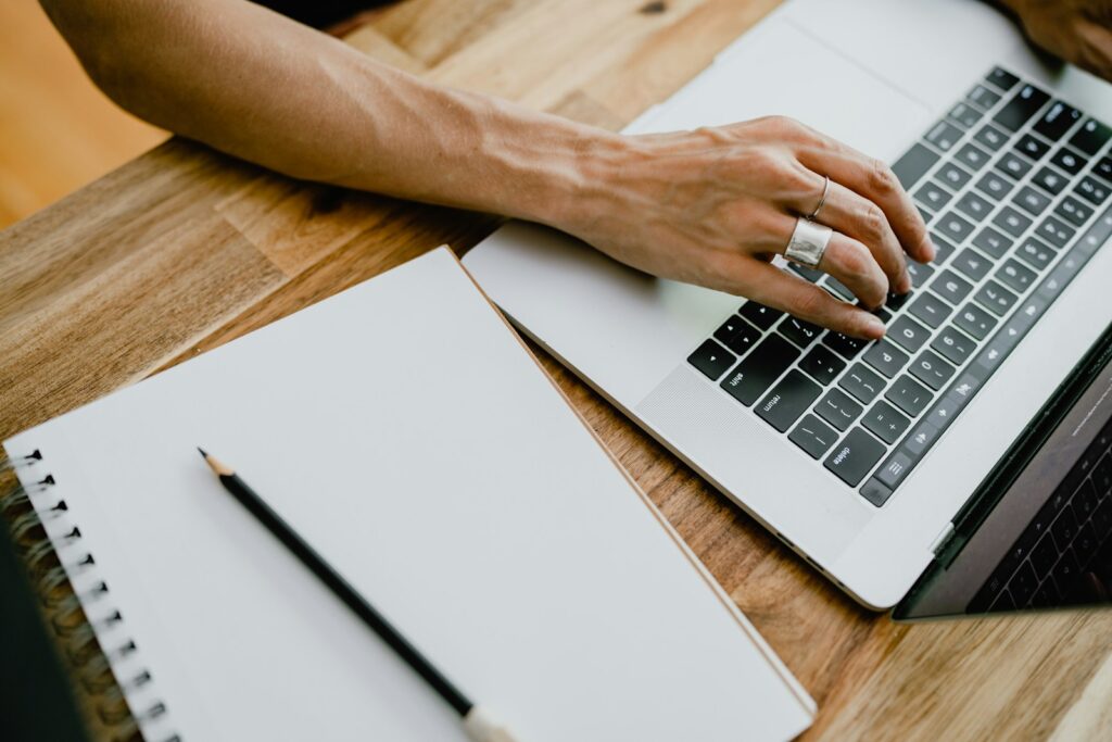 A person typing and editing a document on a laptop at a home desk