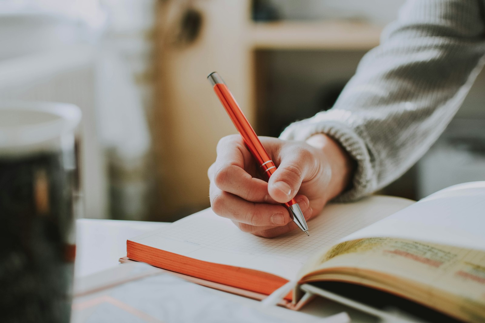 A red pen editing handwritten notes, representing the human review step after AI drafting