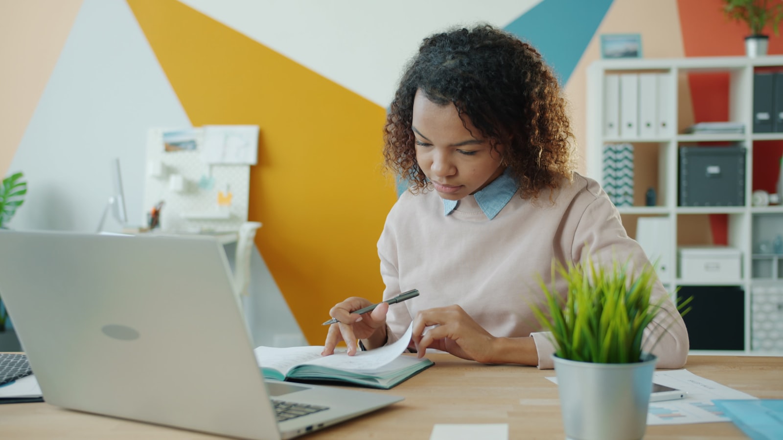 A high school student writing in a notebook at a desk while working on a college essay