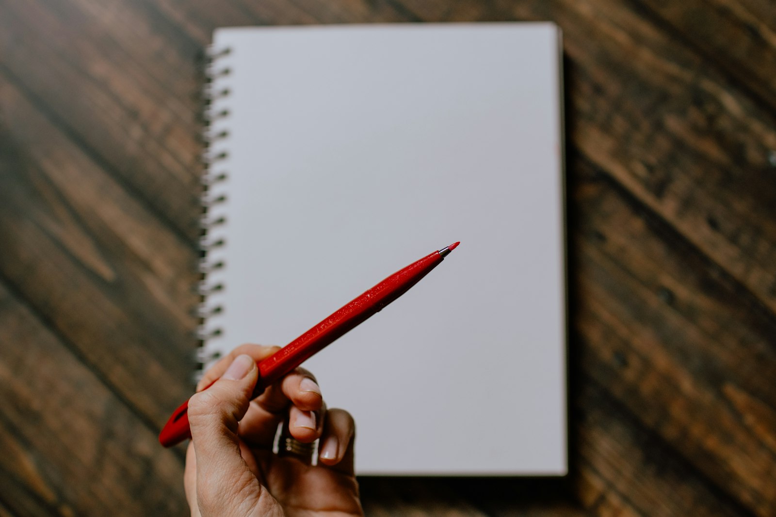 A red pen marking up a blank notebook page, representing manuscript editing