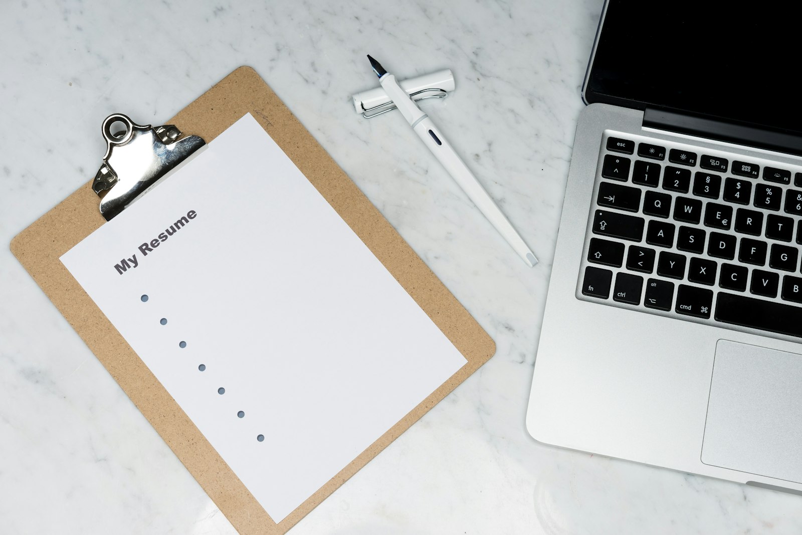 A printed resume next to a laptop on a desk, ready for review
