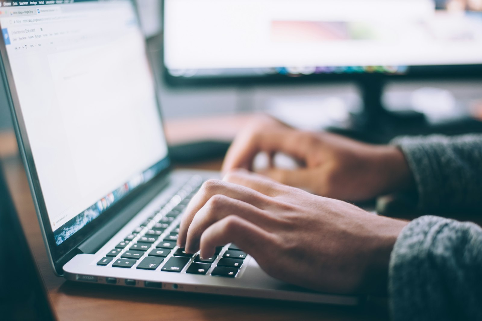A person typing on a laptop while writing their resume