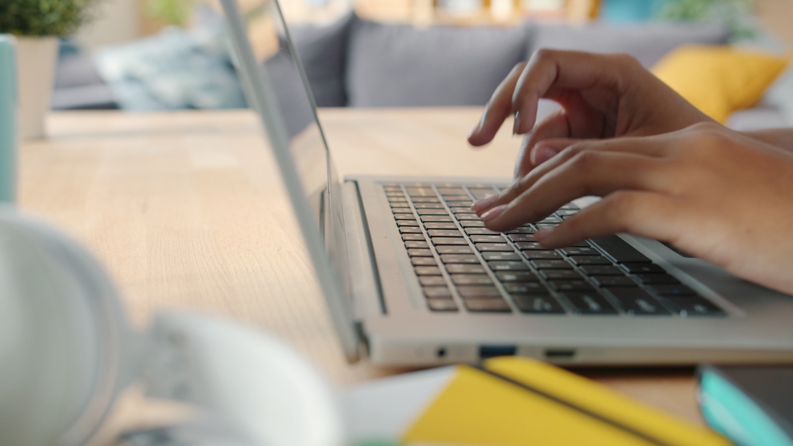 A student's hands typing on a laptop keyboard while revising a college application essay