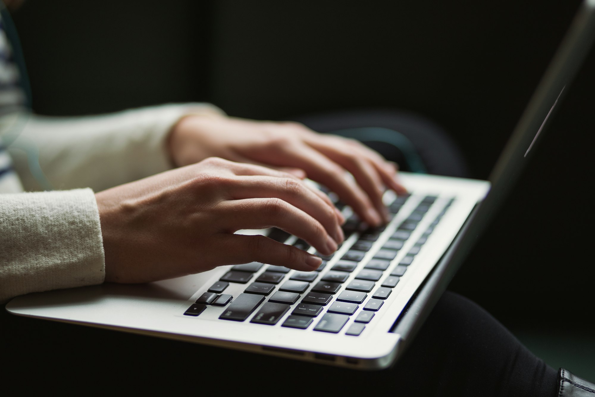 A person typing on a laptop while revising a draft