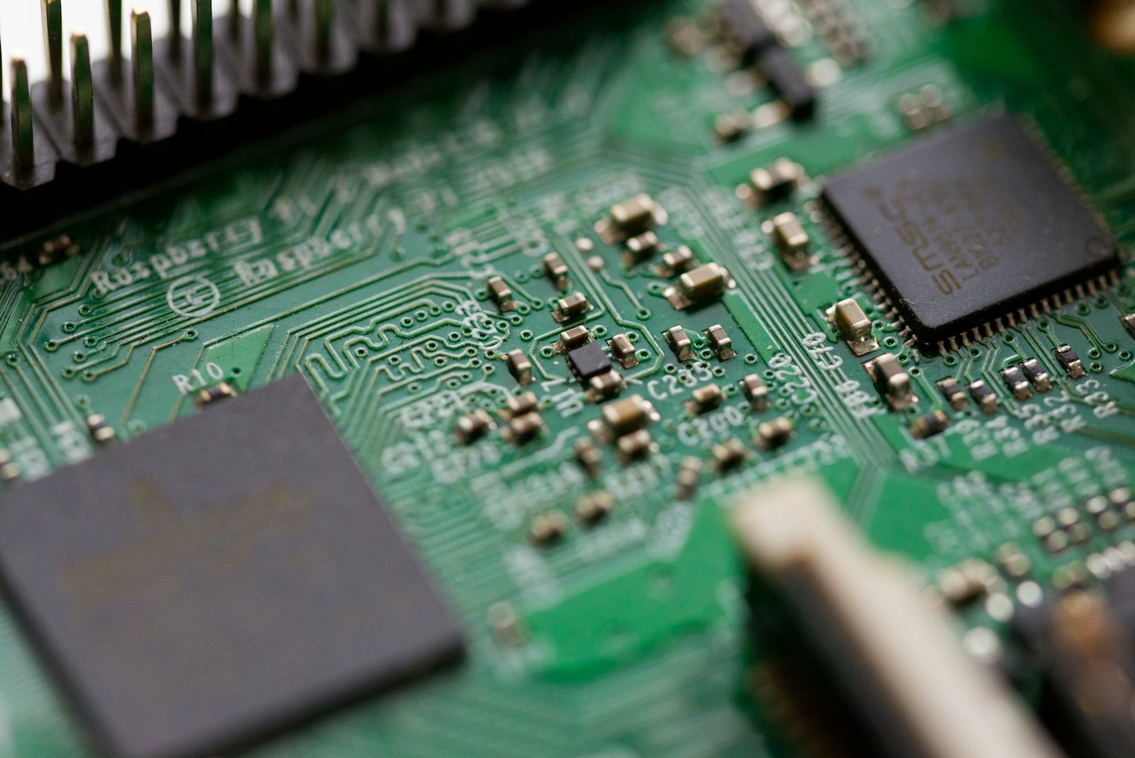 Tilt-shift close-up of a green circuit board with electronic components