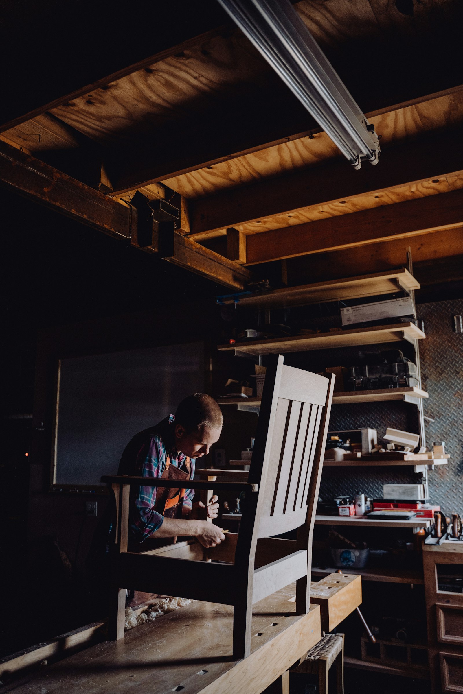 A craftsman working on a wooden chair in a workshop, dovetail joinery in progress