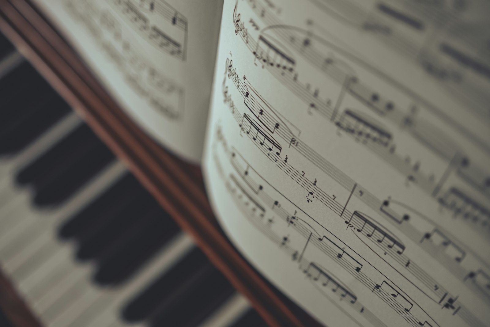 Open book of sheet music with piano in the background