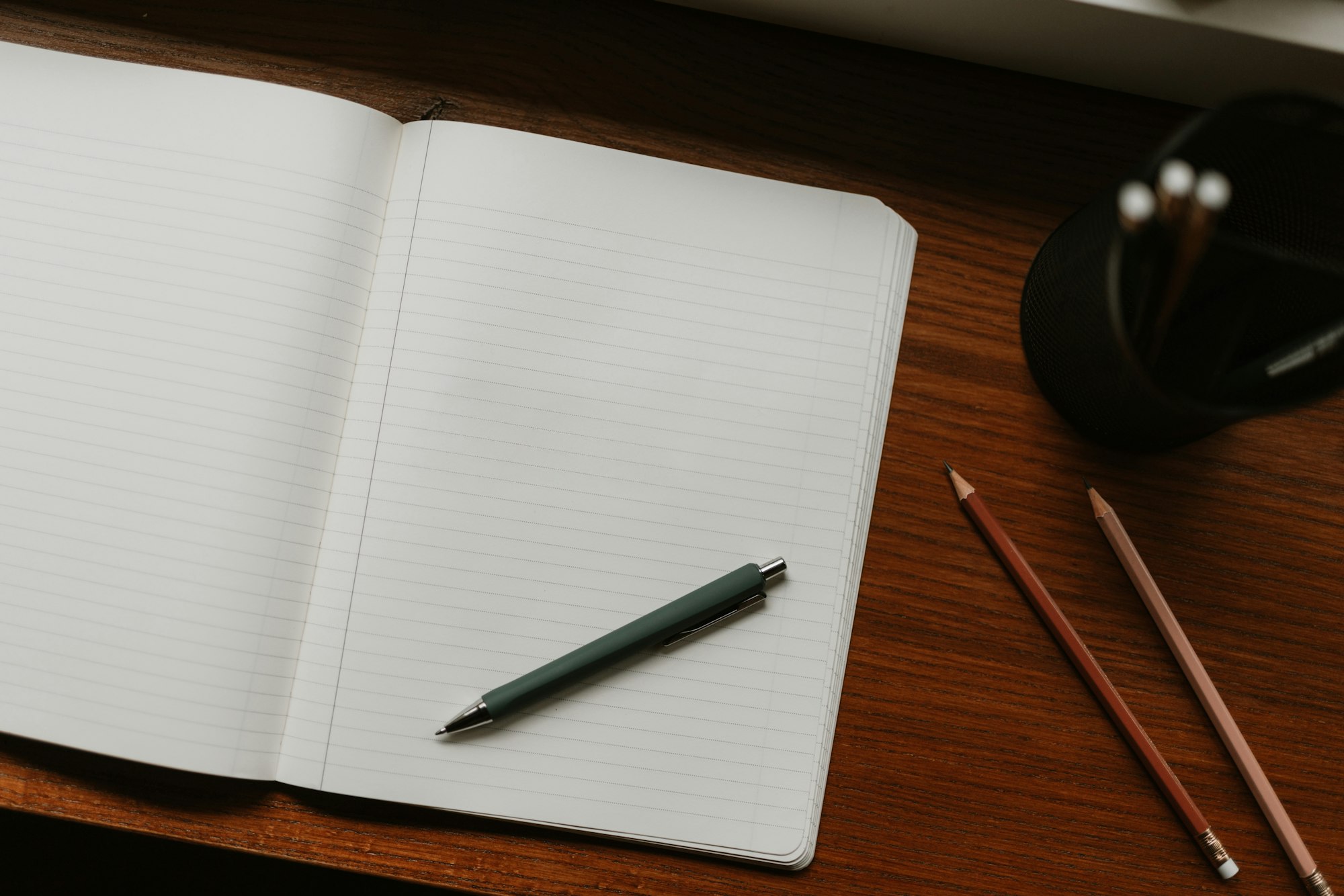 An open notebook with a pen resting across a blank lined page